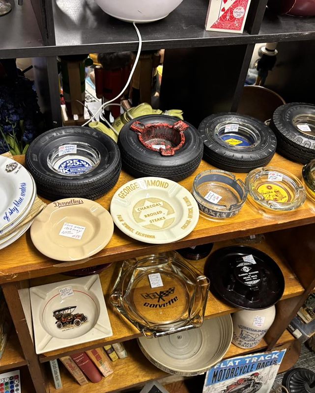 Shelves of vintage ashtrays, including tire ashtrays and a Corvette ashtray