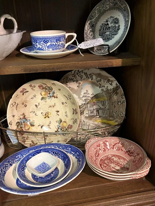 Blue-and-white and pink transferware plates, bowls and a teacup in a wooden cabinet