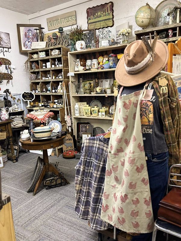 A room of home décor: shelves, signs, a globe, and a hat and apron on a mannequin