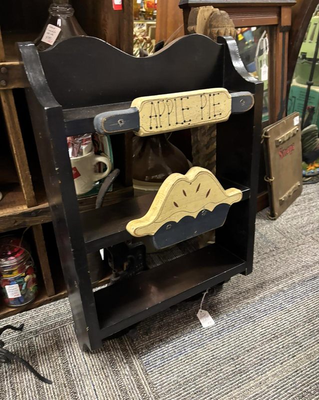 A small black wooden stand with an Apple Pie sign and a wooden pie