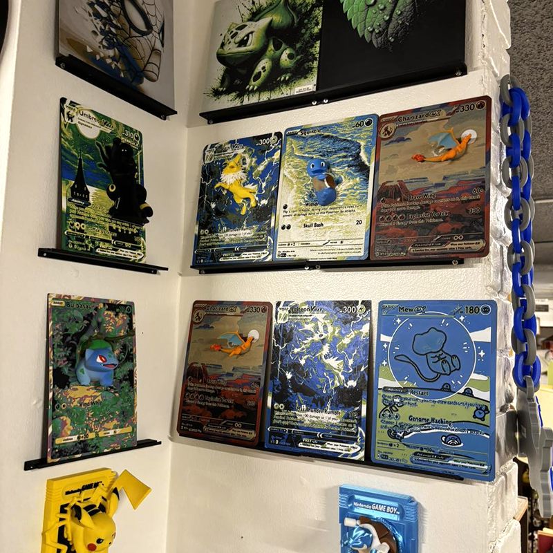 Large Pokémon card-style prints on a wall, with a Pikachu figure below