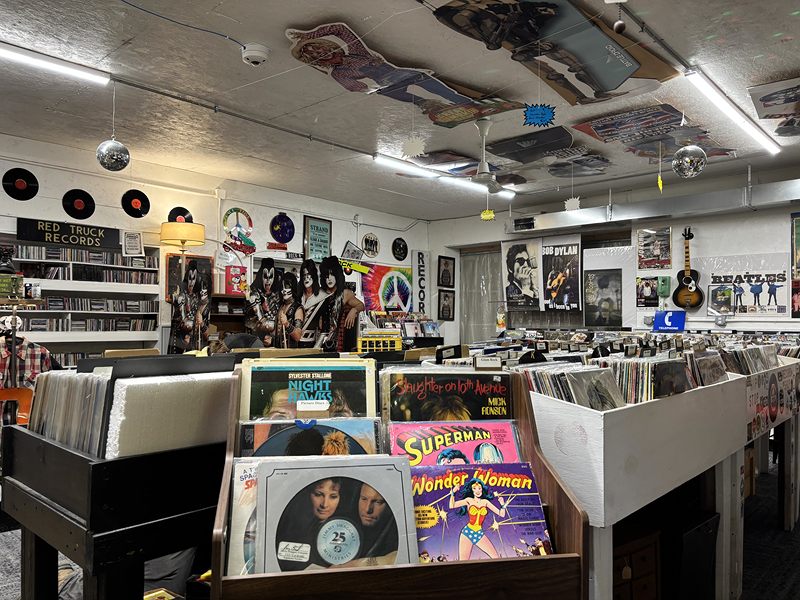 Bins of vinyl records, with Superman and Wonder Woman albums up front and music posters on the walls