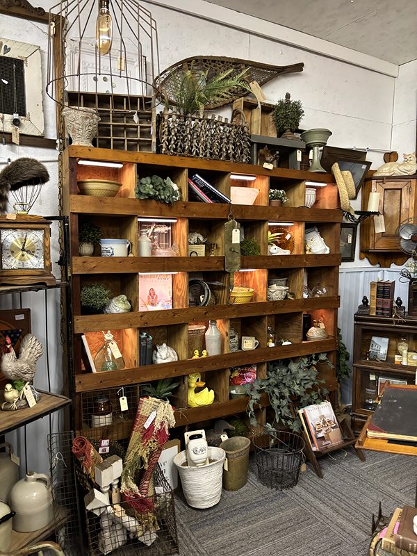 A tall wooden cubby shelf filled with farmhouse décor, crocks and baskets