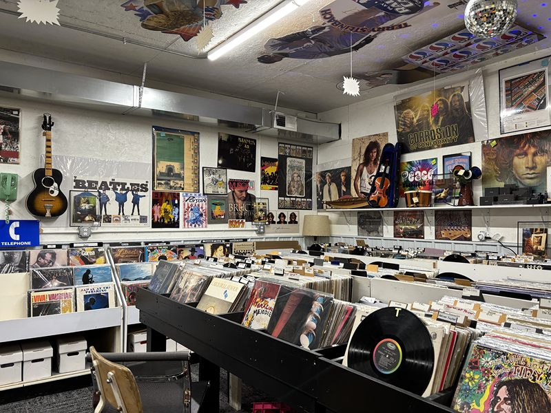 Long rows of vinyl records beneath Beatles and other music posters