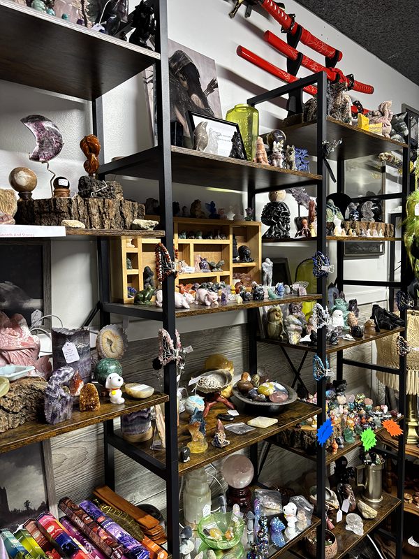 Black metal shelves of crystals, figurines and small curiosities