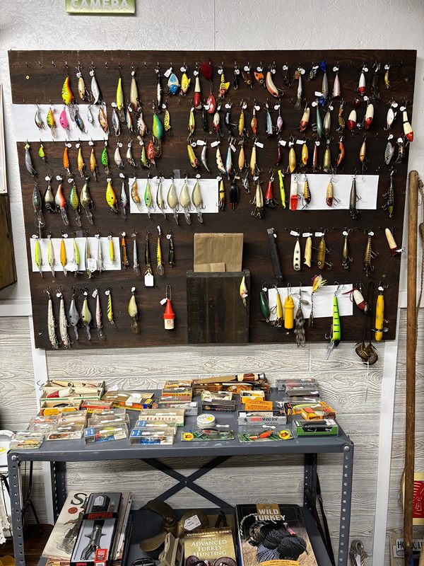 A wall of fishing lures above a table of boxed tackle