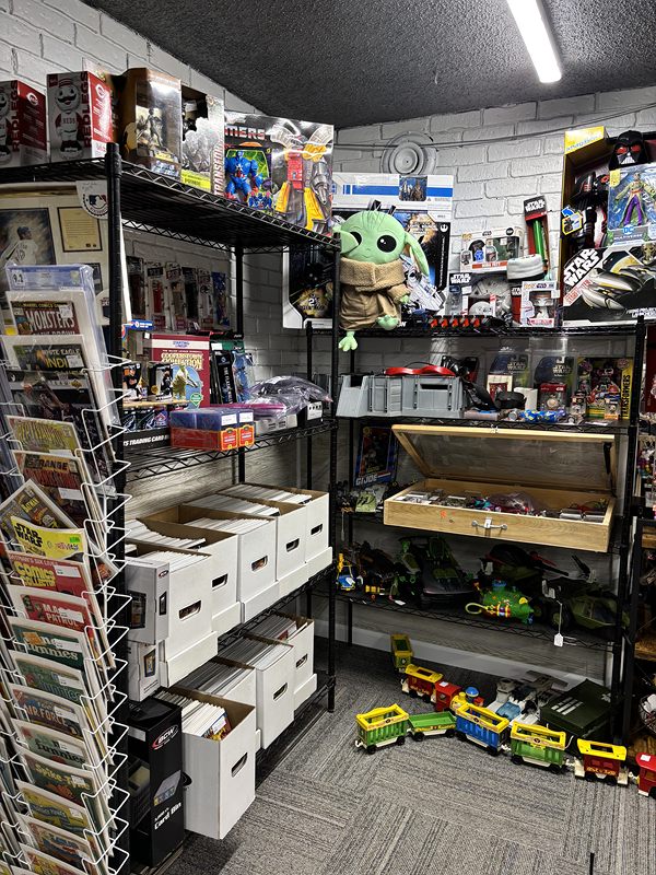 Shelves of boxed toys and action figures, a comic rack and a toy train on the floor