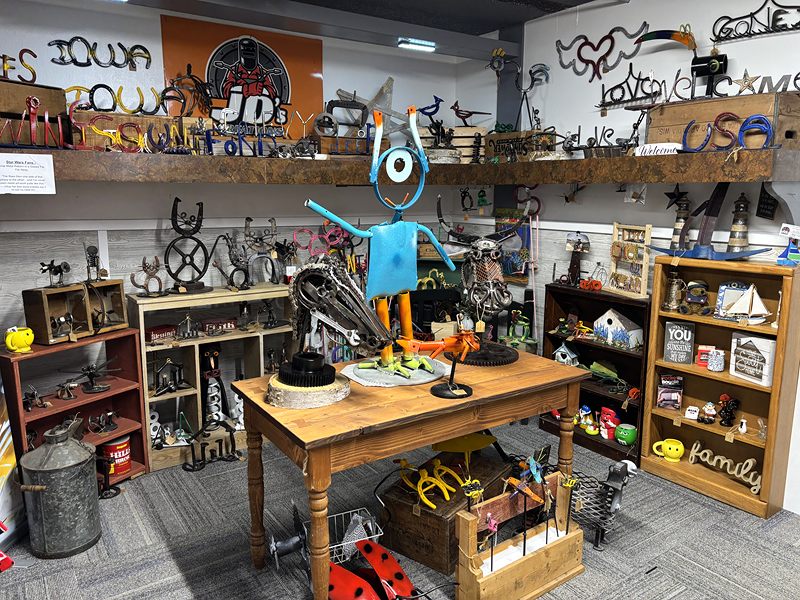 Metal art: cut-metal Iowa and USA signs, sculptures and a robot-like figure on a wooden table