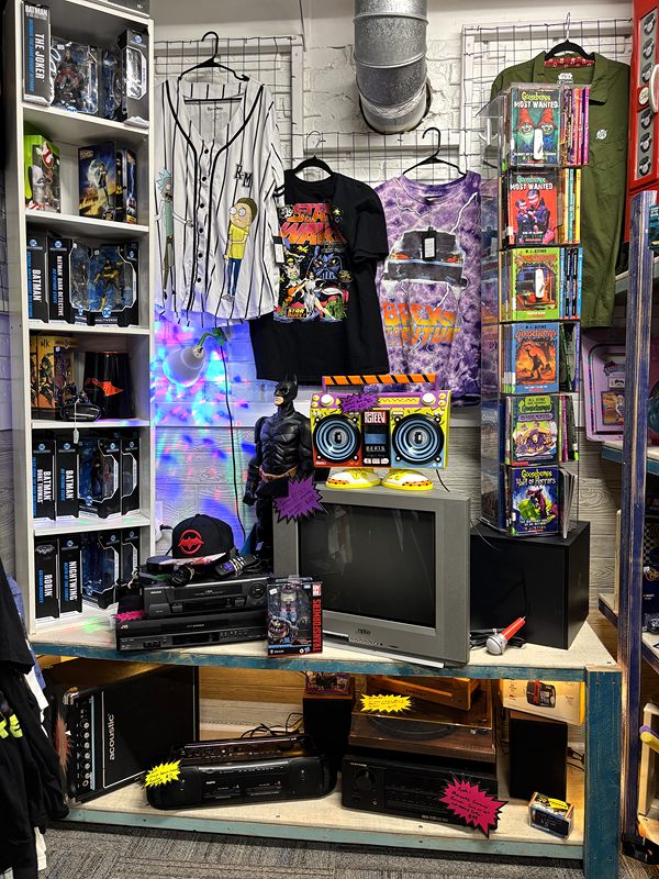 A pop-culture corner with T-shirts, action figures, a boombox and an old television