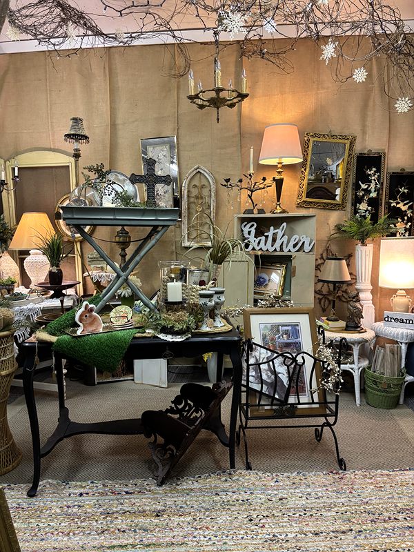 A cozy display with a small table, lamps, a Gather sign and framed art