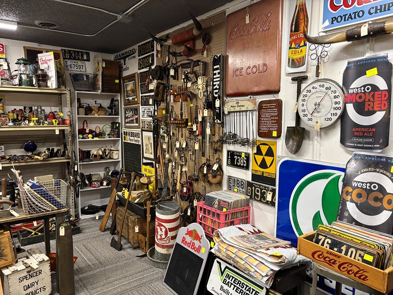 A wall of vintage advertising signs, old tools and license plates