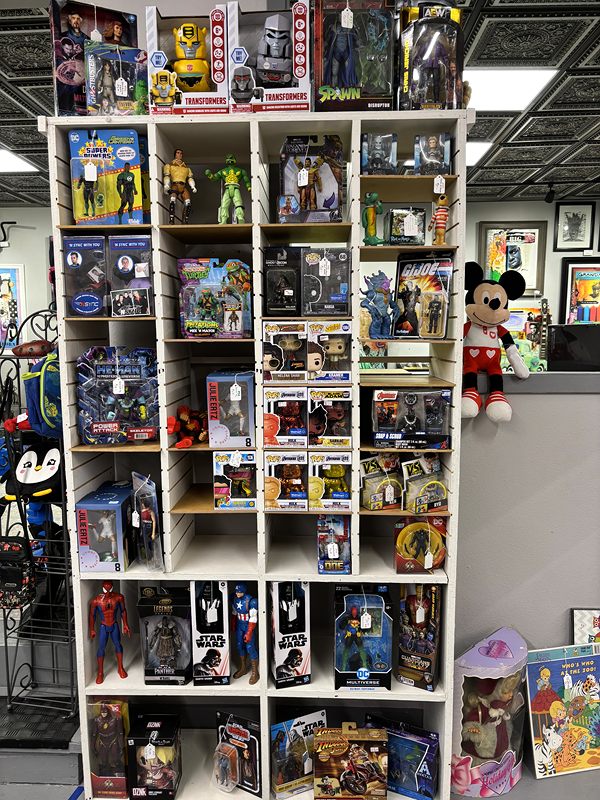 White cubbies of boxed action figures, with a Mickey Mouse plush on top