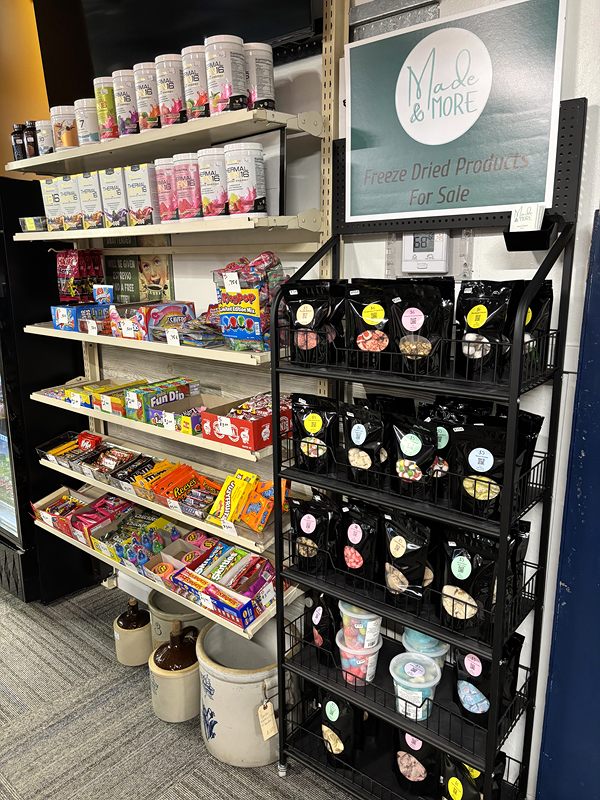 Shelves of candy and packaged treats beside a wire rack of snacks