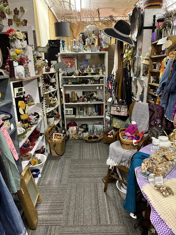 A narrow aisle of shelves with hats, baskets and linens